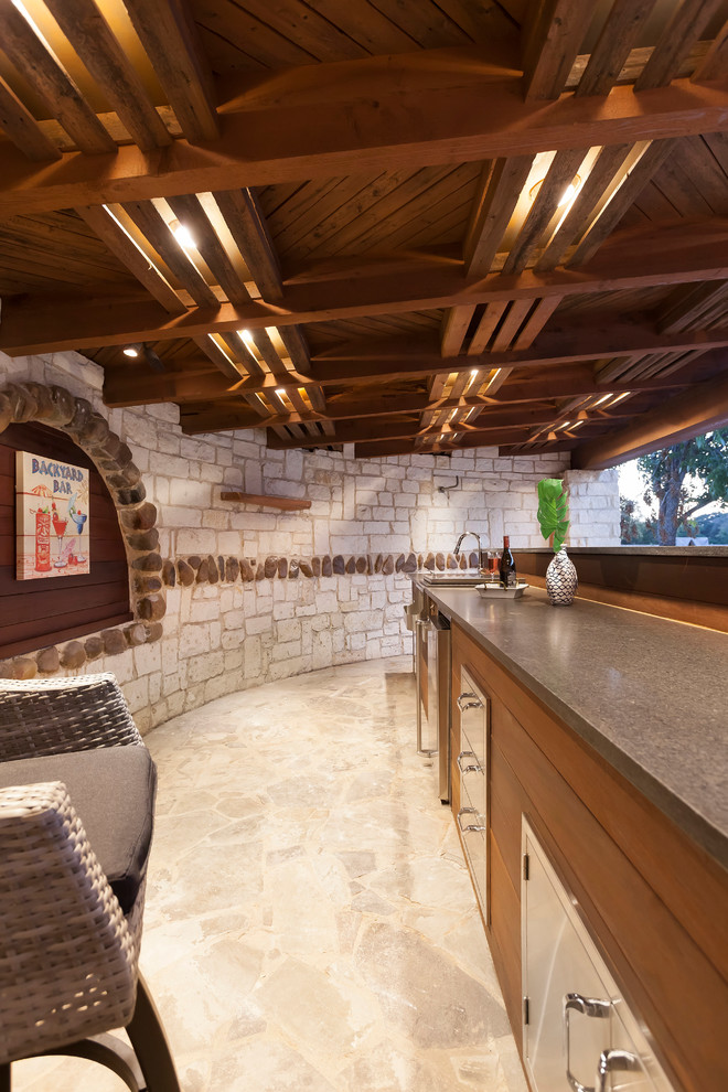 Aménagement d'une grande terrasse arrière contemporaine avec une cuisine d'été, des pavés en pierre naturelle et une pergola.