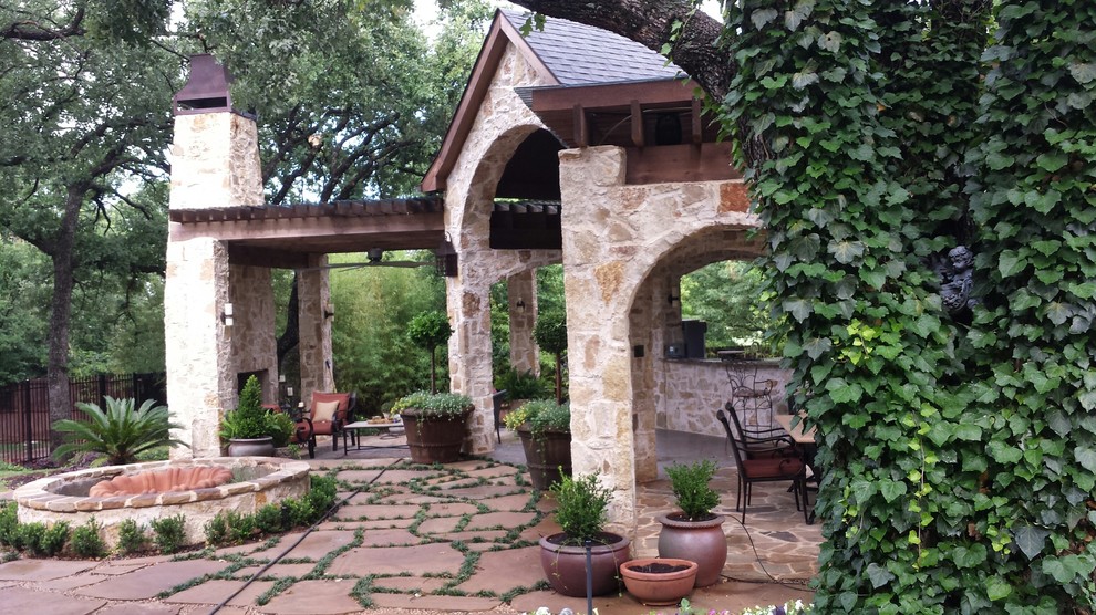 Large elegant backyard stone patio photo in Dallas with a roof extension