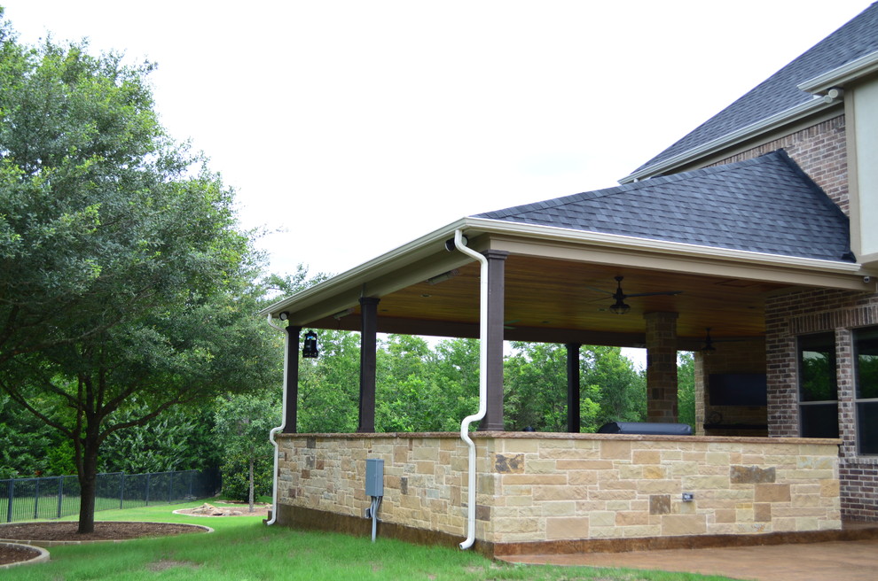 Foto di un ampio patio o portico bohémian dietro casa con un caminetto, cemento stampato e un tetto a sbalzo