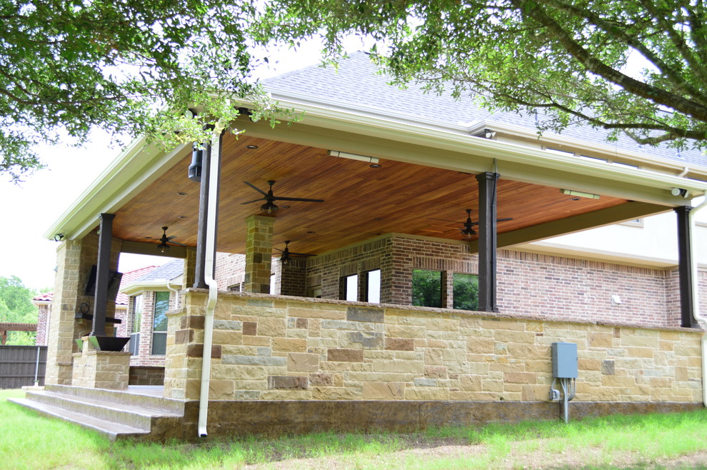 Esempio di un ampio patio o portico boho chic dietro casa con un caminetto, cemento stampato e un tetto a sbalzo