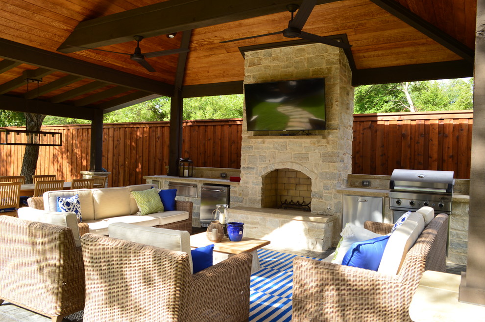 Réalisation d'une très grande terrasse arrière champêtre avec une cuisine d'été et des pavés en pierre naturelle.