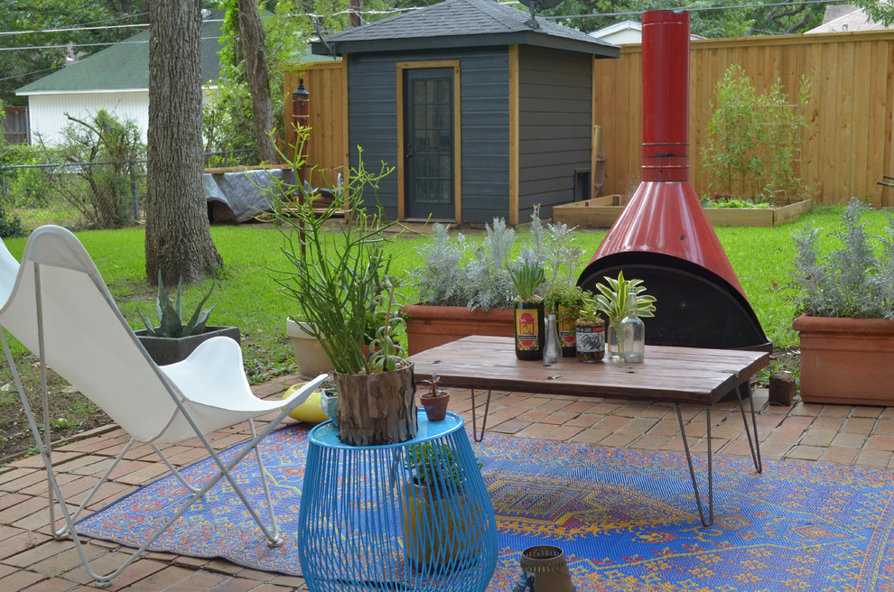 This is an example of a bohemian patio in Dallas with a fire feature, brick paving and no cover.