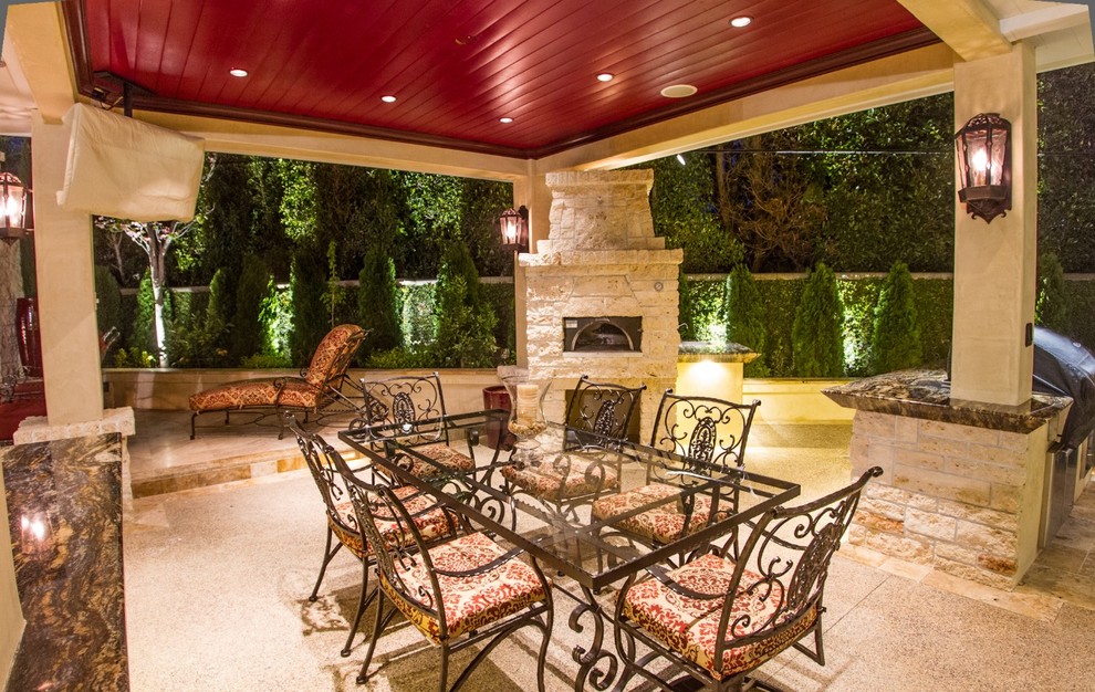 Modelo de patio tropical grande en patio trasero con cocina exterior, adoquines de piedra natural y cenador