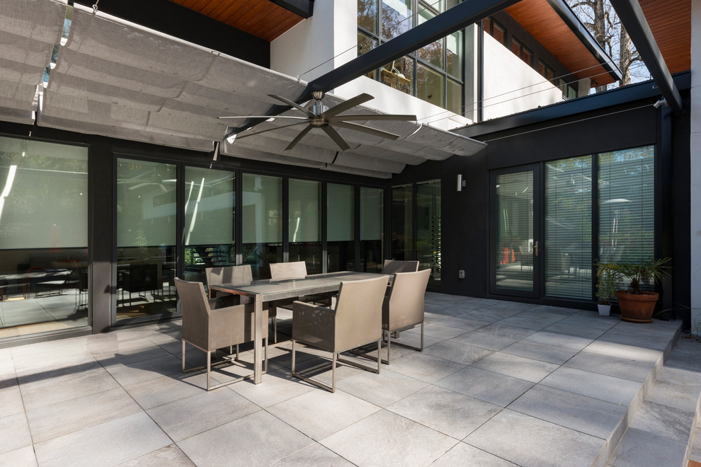 Immagine di un patio o portico design dietro casa con un parasole e pavimentazioni in cemento