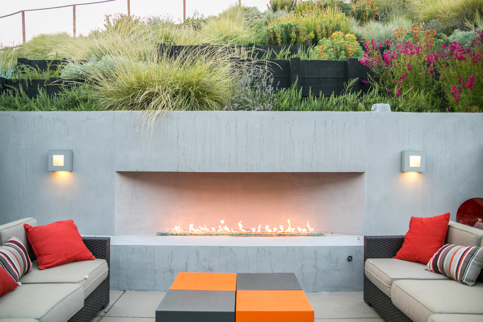 This is an example of a medium sized contemporary back patio in San Francisco with a fire feature and concrete paving.