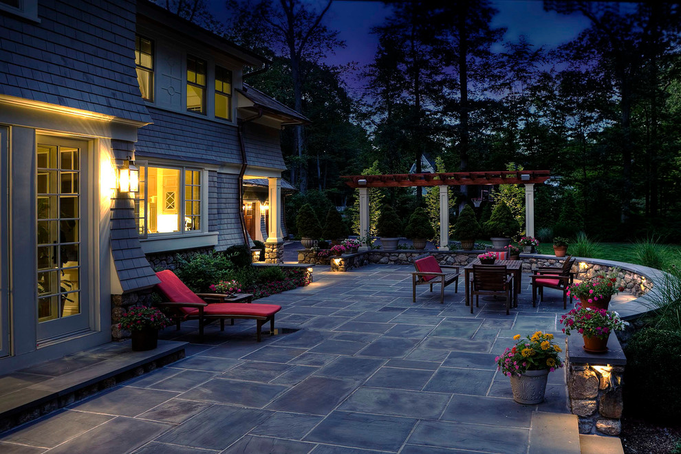 Modelo de patio clásico grande en patio trasero con jardín de macetas, adoquines de piedra natural y pérgola