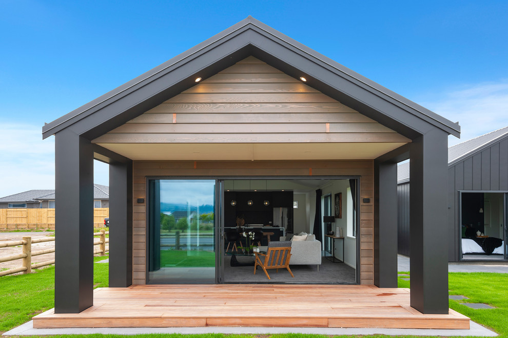 Idée de décoration pour une terrasse en bois arrière minimaliste de taille moyenne avec une extension de toiture.