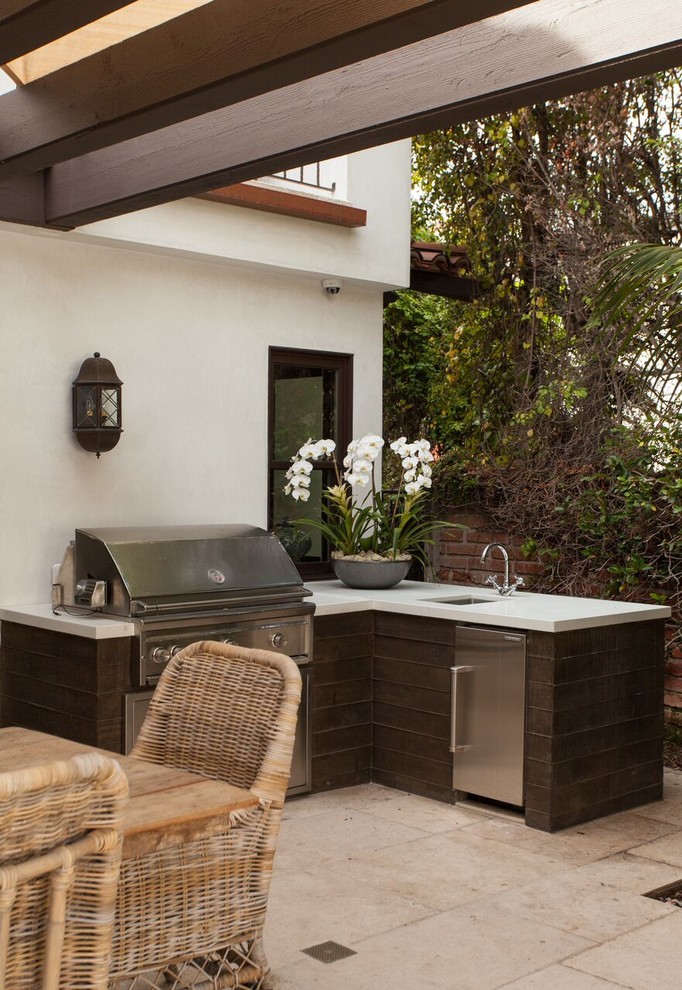 Large mediterranean back patio in Orange County with an outdoor kitchen, natural stone paving and a pergola.