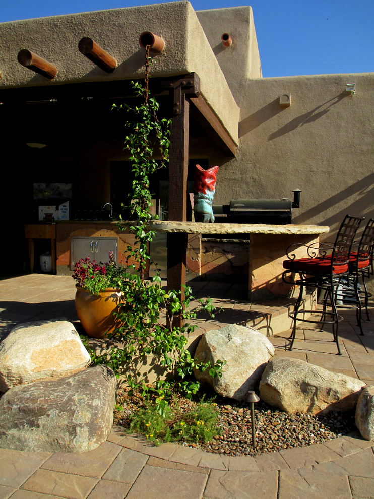 Large tuscan backyard stone patio photo in Phoenix with a roof extension