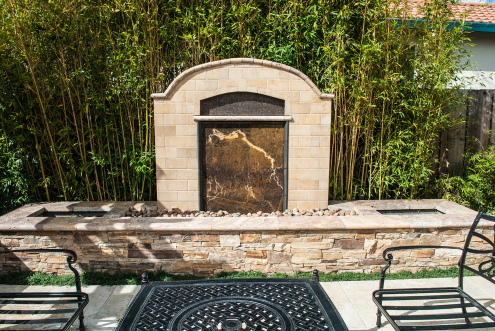 Ejemplo de patio clásico pequeño sin cubierta en patio trasero con fuente y adoquines de piedra natural
