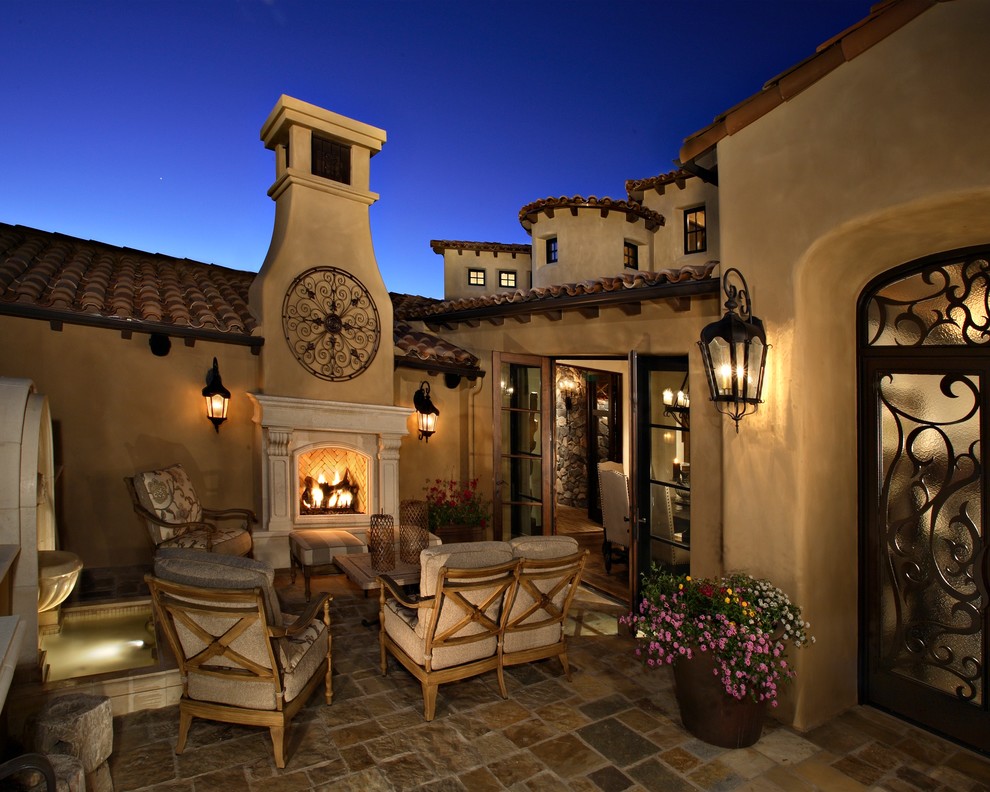 Design ideas for a large mediterranean courtyard patio in Phoenix with natural stone paving, no cover and a fireplace.