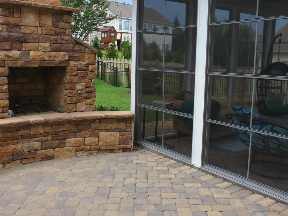 Immagine di un patio o portico classico di medie dimensioni e dietro casa con un focolare e pavimentazioni in mattoni
