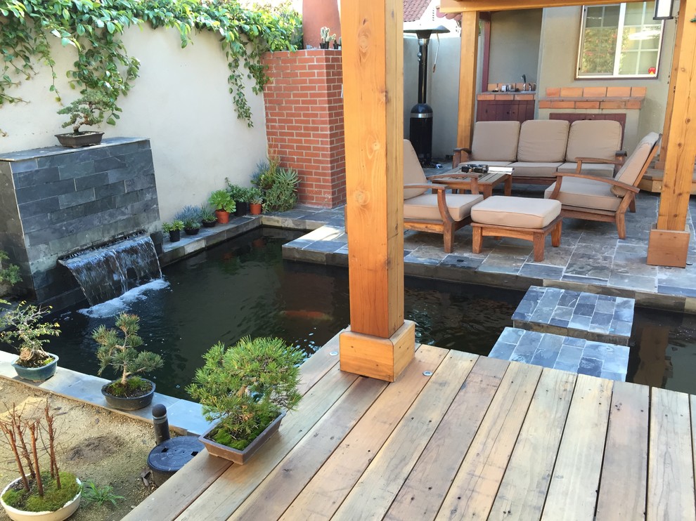 Cette photo montre une terrasse arrière asiatique de taille moyenne avec un point d'eau, du carrelage et une pergola.