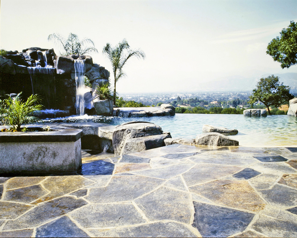 Photo of a world-inspired back patio in Orange County with a water feature, stamped concrete and a pergola.