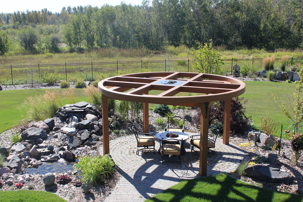 Inspiration for a mid-sized timeless backyard brick patio fountain remodel in Edmonton with a pergola