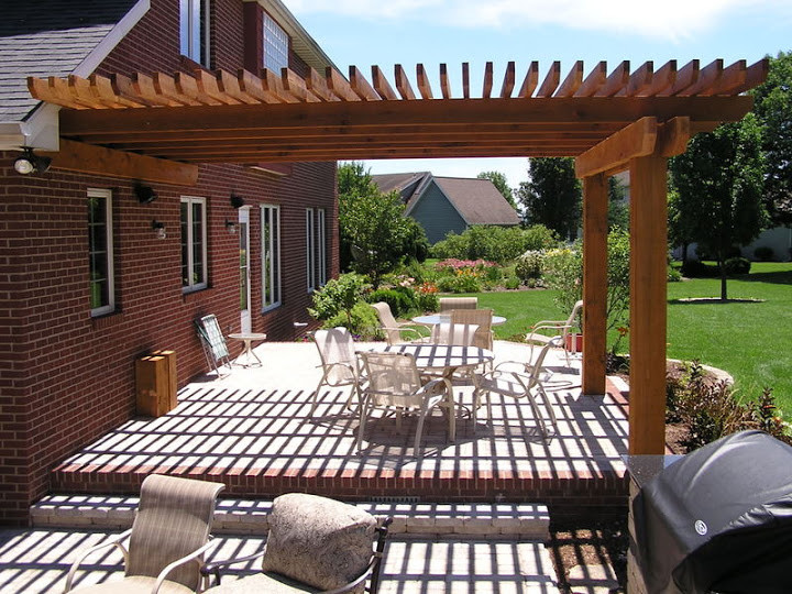 This is an example of a large traditional back patio in Chicago with an outdoor kitchen, brick paving and a pergola.