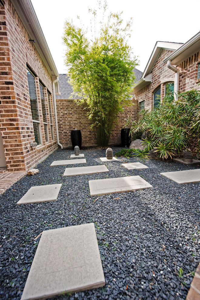 This is an example of a small courtyard patio in Houston with gravel and no cover.