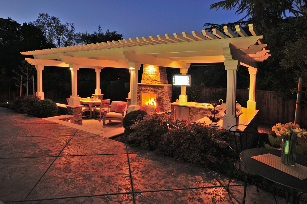 Cette photo montre une grande terrasse arrière chic avec des pavés en pierre naturelle, une cuisine d'été et une pergola.