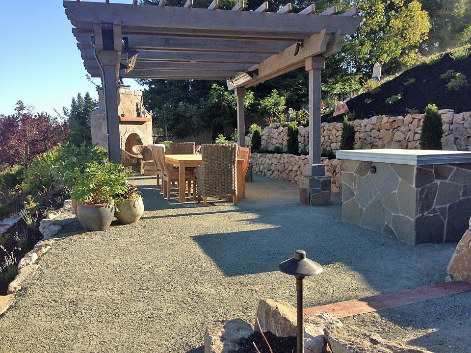 Foto di un ampio patio o portico chic dietro casa con un focolare, graniglia di granito e una pergola