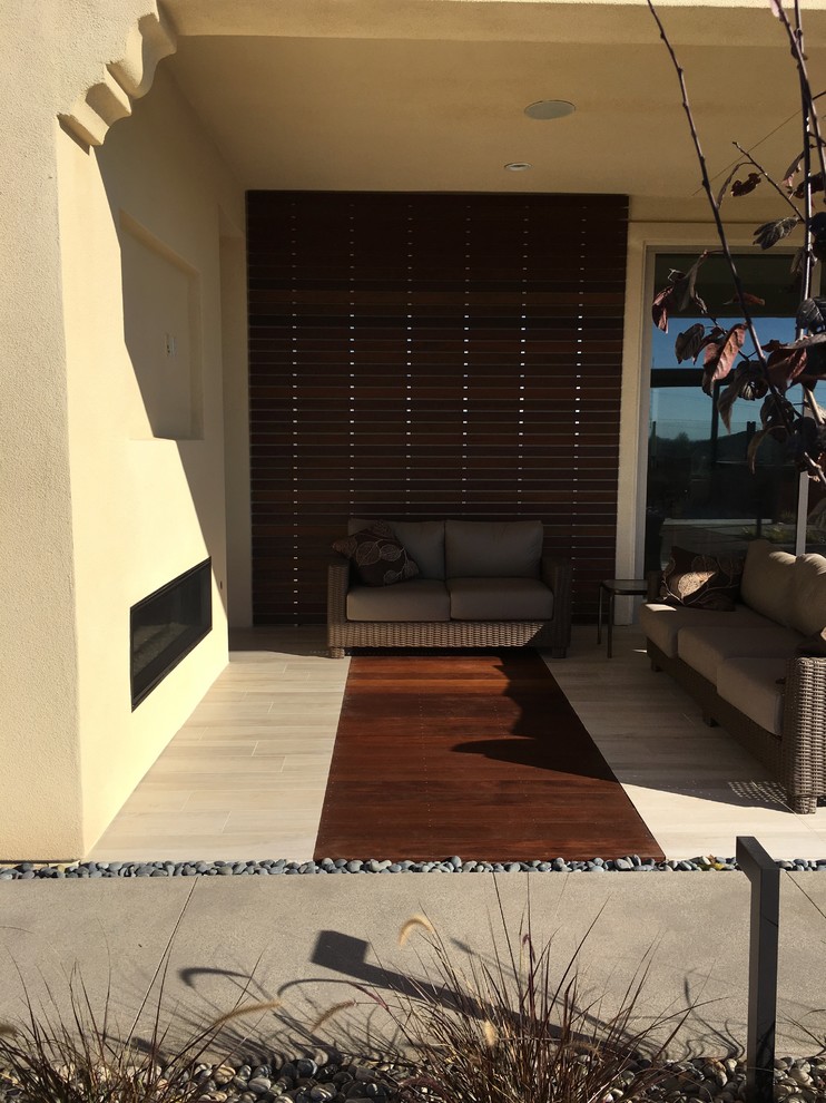 Kleiner, Überdachter Moderner Patio hinter dem Haus mit Feuerstelle und Dielen in San Diego