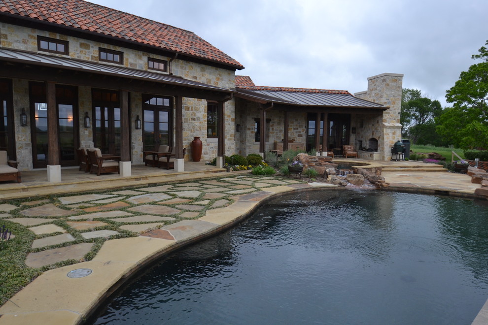 Example of a mid-sized backyard stone patio fountain design in Dallas with a roof extension