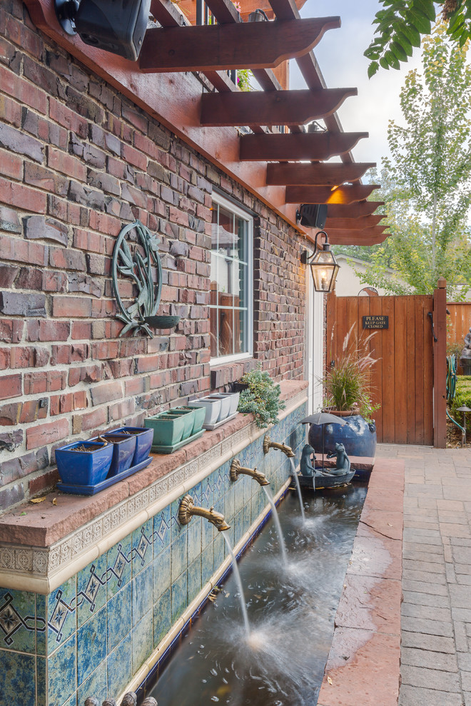 Inspiration for a timeless backyard stone patio fountain remodel in Denver with an awning