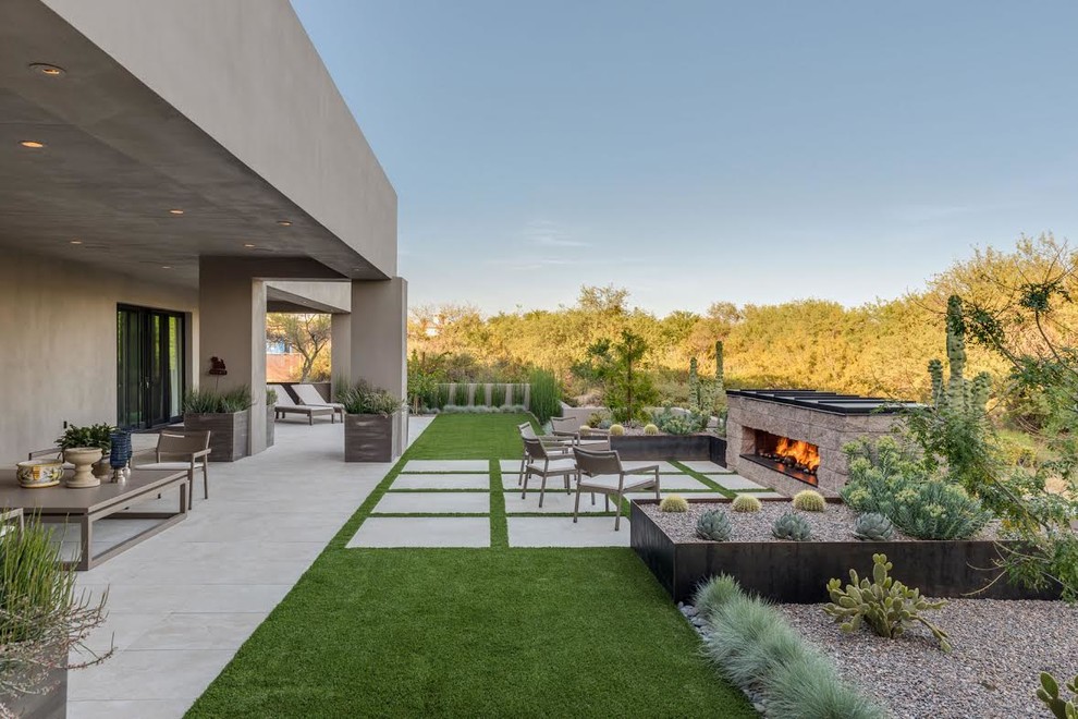 Inspiration pour une grande terrasse arrière minimaliste avec un foyer extérieur, une dalle de béton et une extension de toiture.