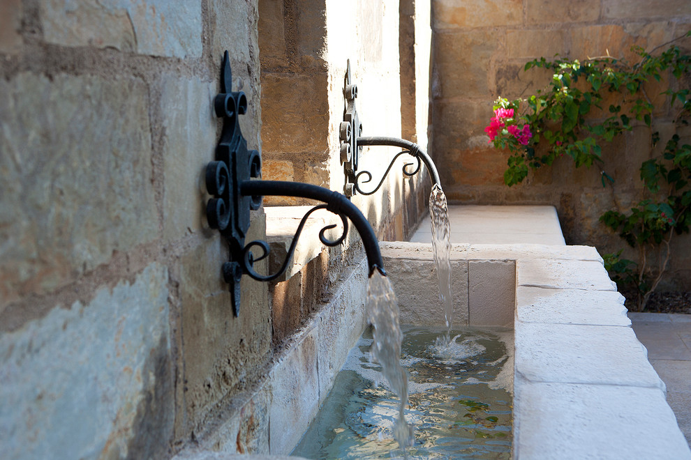 Ispirazione per un ampio patio o portico mediterraneo con fontane e pavimentazioni in pietra naturale