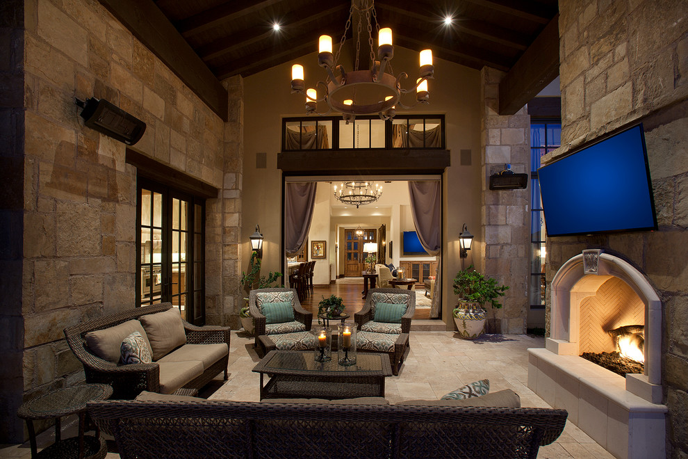 Photo of an expansive mediterranean side patio in Phoenix with a roof extension, natural stone paving and a fireplace.