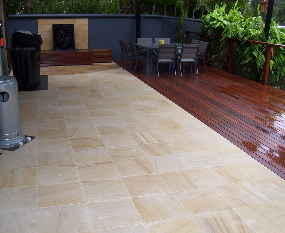 Medium sized modern back patio in Gold Coast - Tweed with a water feature, natural stone paving and a roof extension.
