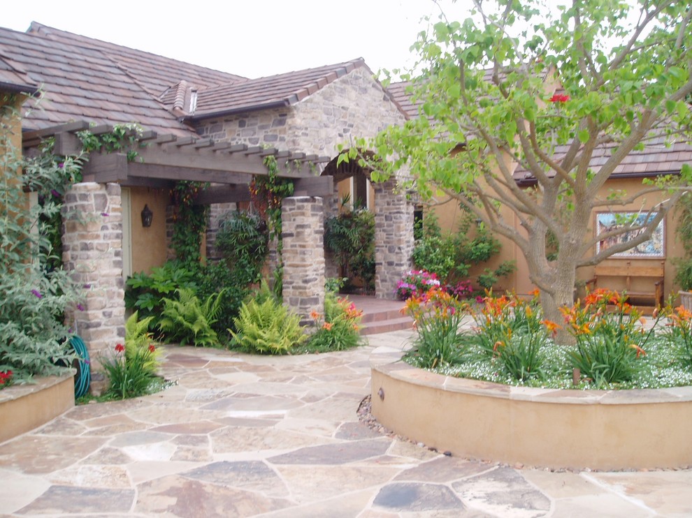 Mediterranean courtyard patio in San Diego with natural stone paving and a pergola.