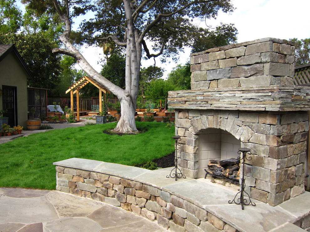 Immagine di un patio o portico chic dietro casa e di medie dimensioni con un focolare e pavimentazioni in pietra naturale