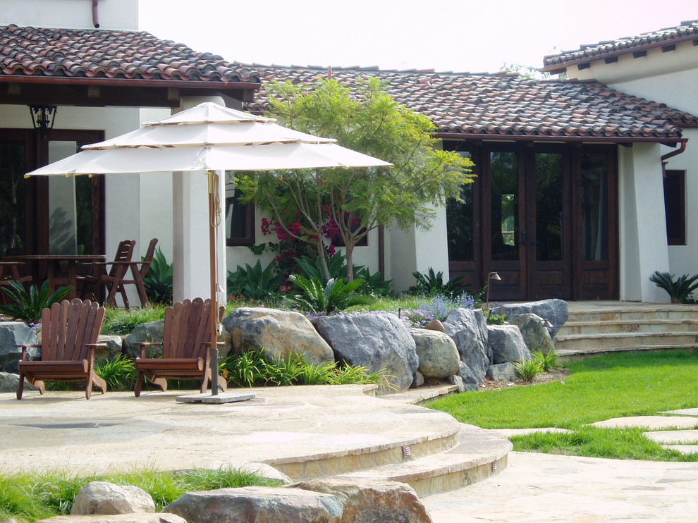 Пример оригинального дизайна: большой двор на заднем дворе в средиземноморском стиле с покрытием из каменной брусчатки без защиты от солнца