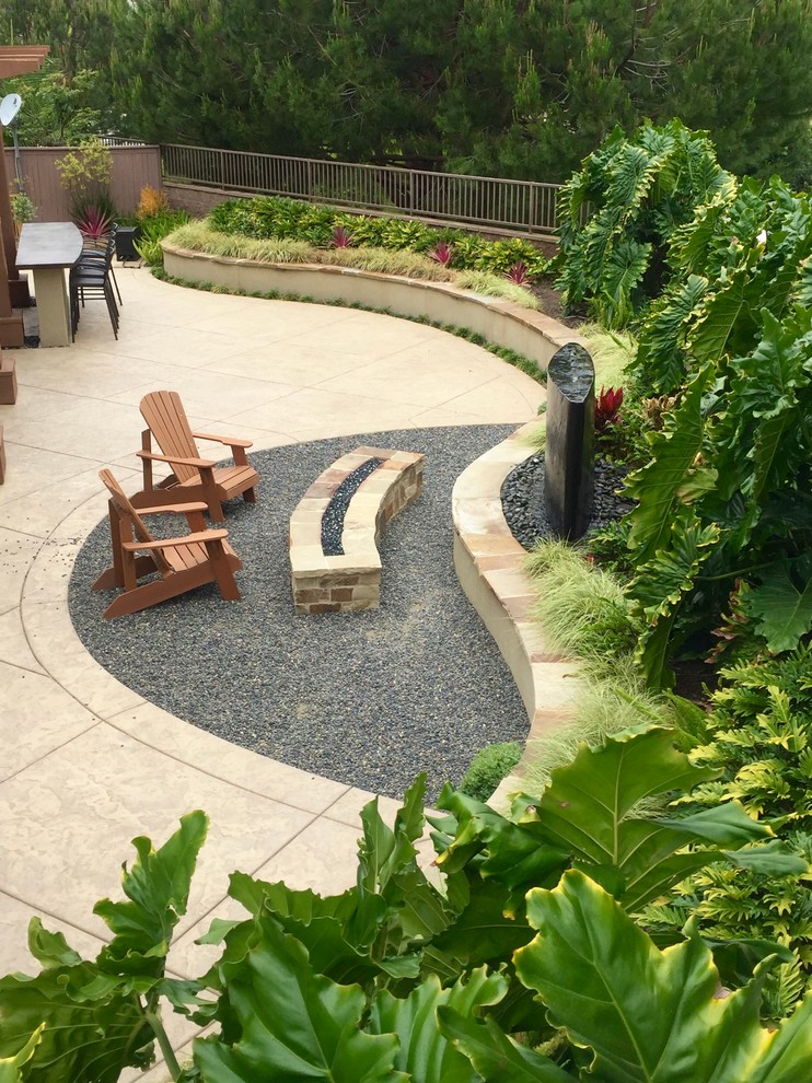 This is an example of a medium sized world-inspired back patio in San Diego with a fire feature, gravel and a roof extension.