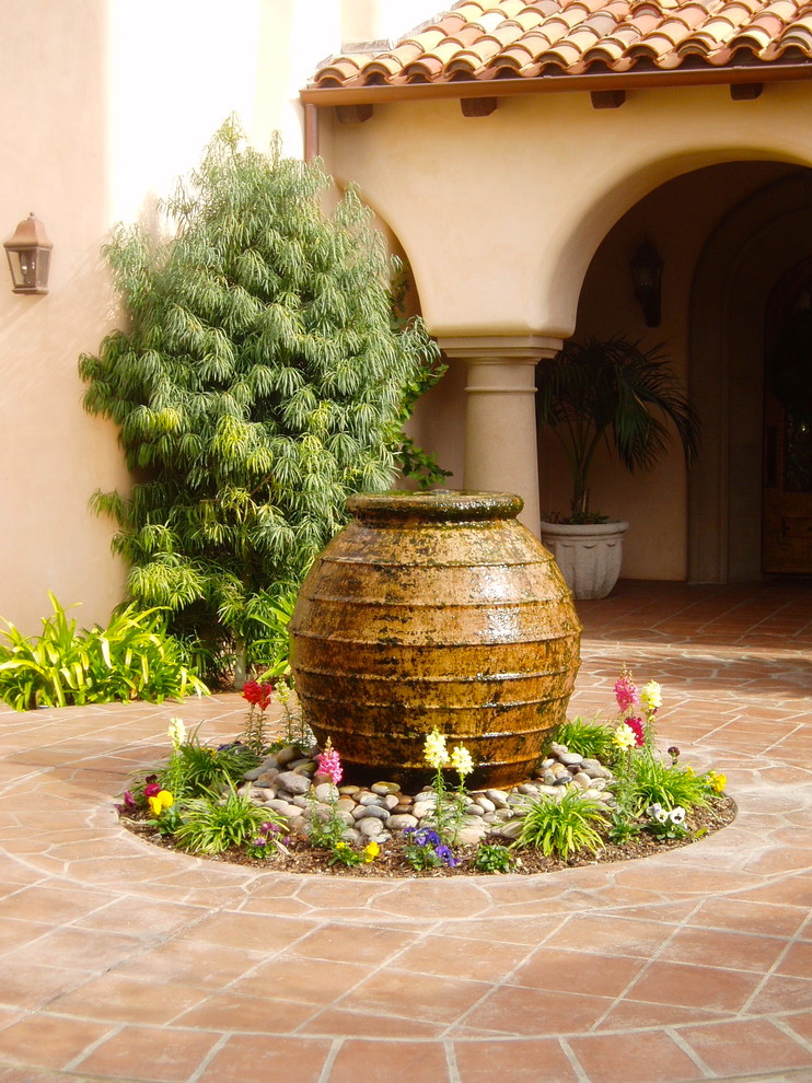 Imagen de patio mediterráneo en patio con fuente y suelo de baldosas