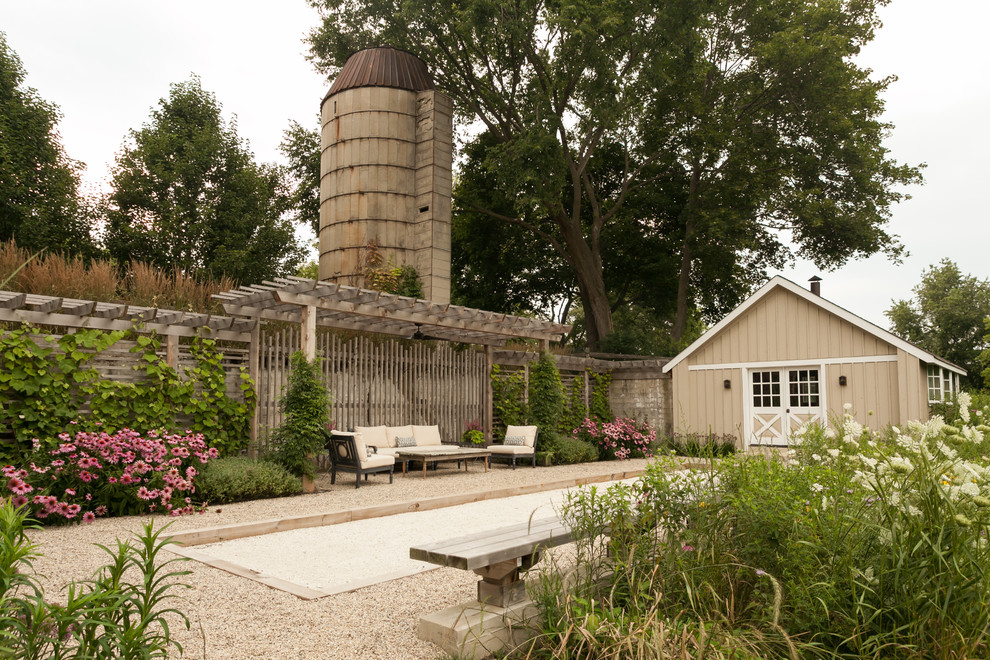 Ejemplo de patio de estilo de casa de campo de tamaño medio en patio lateral con gravilla y pérgola