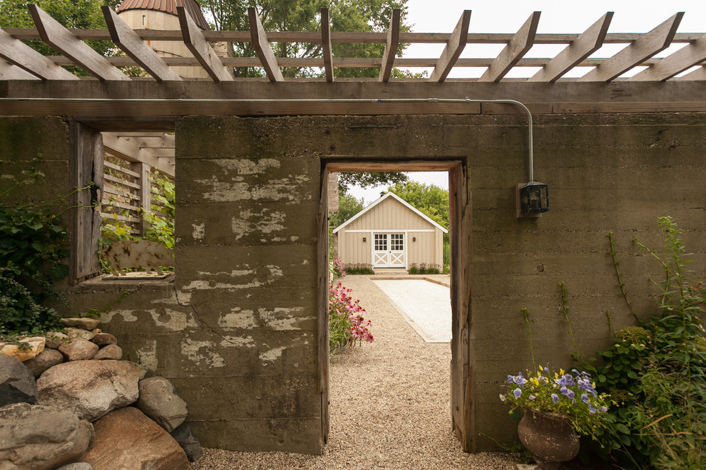 Imagen de patio de estilo de casa de campo de tamaño medio en patio lateral con gravilla y pérgola