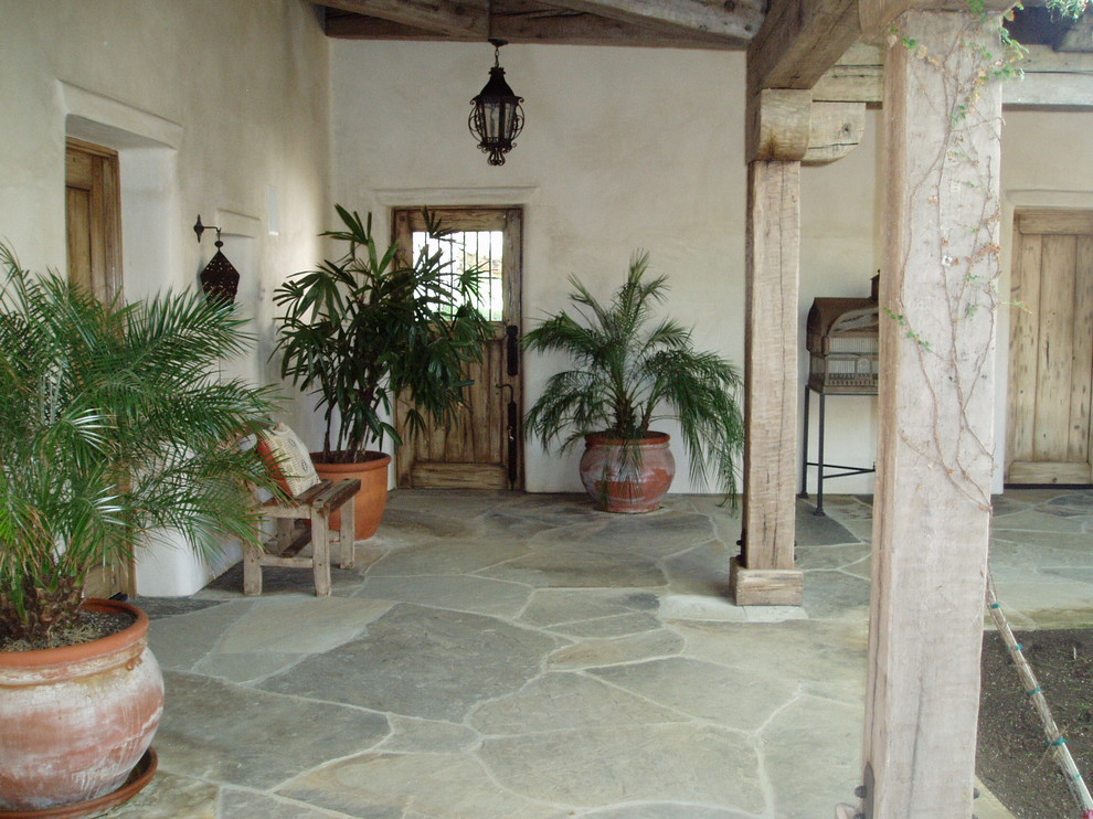 Design ideas for a mediterranean courtyard patio in San Diego with natural stone paving and a roof extension.