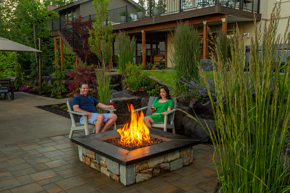 Large classic back patio in Seattle with a fire feature, natural stone paving and no cover.