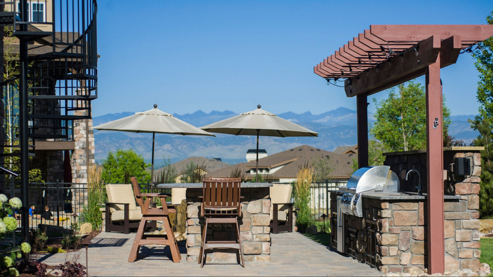 Inspiration pour une terrasse arrière chalet de taille moyenne avec une cuisine d'été, des pavés en béton et une pergola.