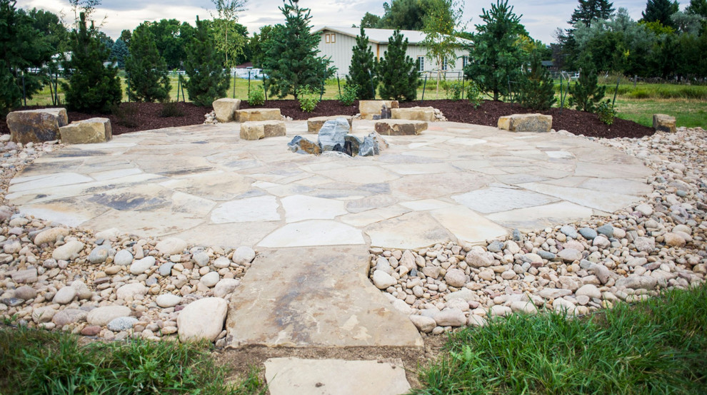 Photo of a large rustic back patio in Denver with natural stone paving and no cover.