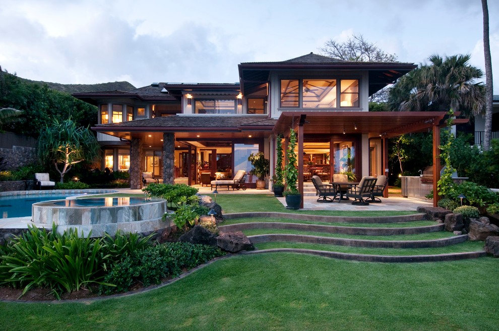Large world-inspired back patio in Hawaii with a roof extension and natural stone paving.