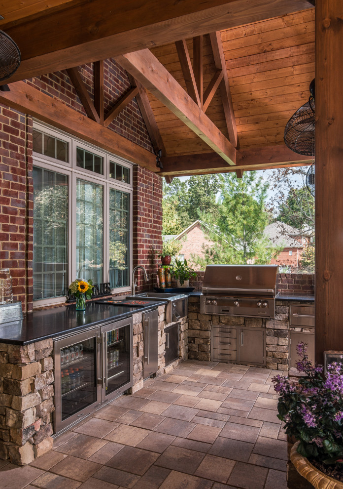 Cette image montre une grande terrasse arrière chalet avec une cuisine d'été, une extension de toiture et du carrelage.