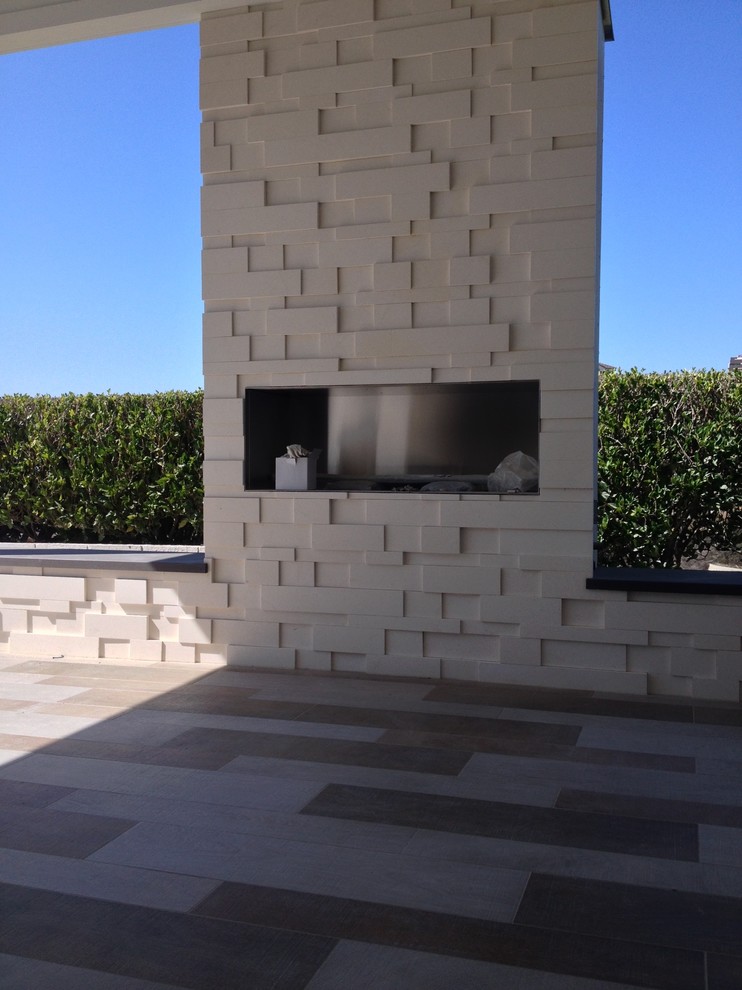 Großer, Überdachter Moderner Patio hinter dem Haus mit Feuerstelle und Natursteinplatten in San Diego