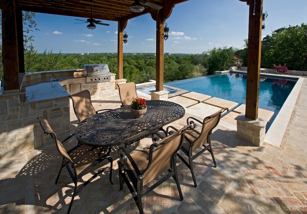 Example of a mid-sized classic backyard brick patio kitchen design in Austin with an awning