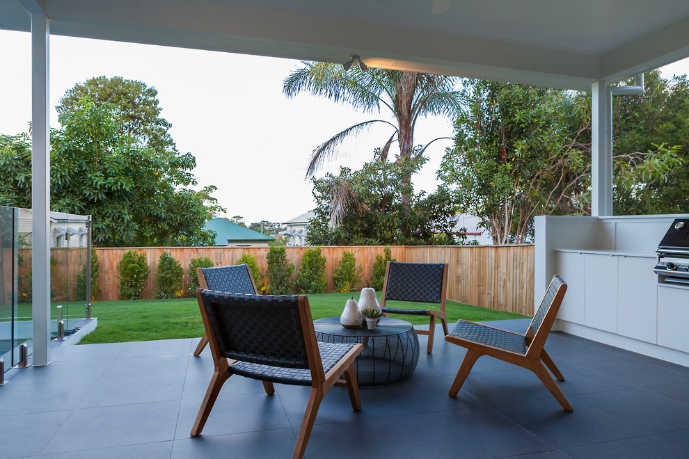 Photo of a scandi back patio in Brisbane with an outdoor kitchen, concrete paving and an awning.