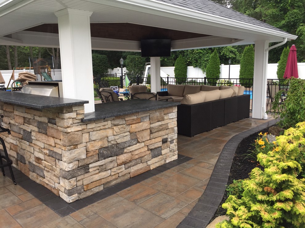 Example of a large classic backyard concrete paver patio kitchen design in New York with a gazebo