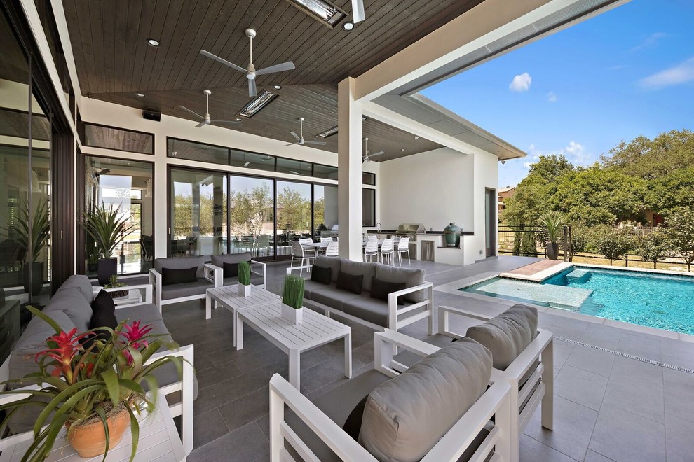 Immagine di un grande patio o portico minimal dietro casa con piastrelle e un tetto a sbalzo