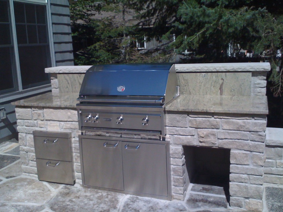 Photo of a medium sized traditional back patio in Chicago with an outdoor kitchen and natural stone paving.