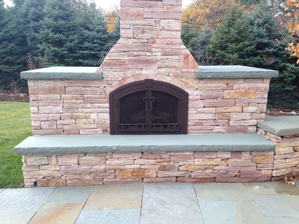 Design ideas for a large classic back patio in New York with a fire feature, natural stone paving and no cover.